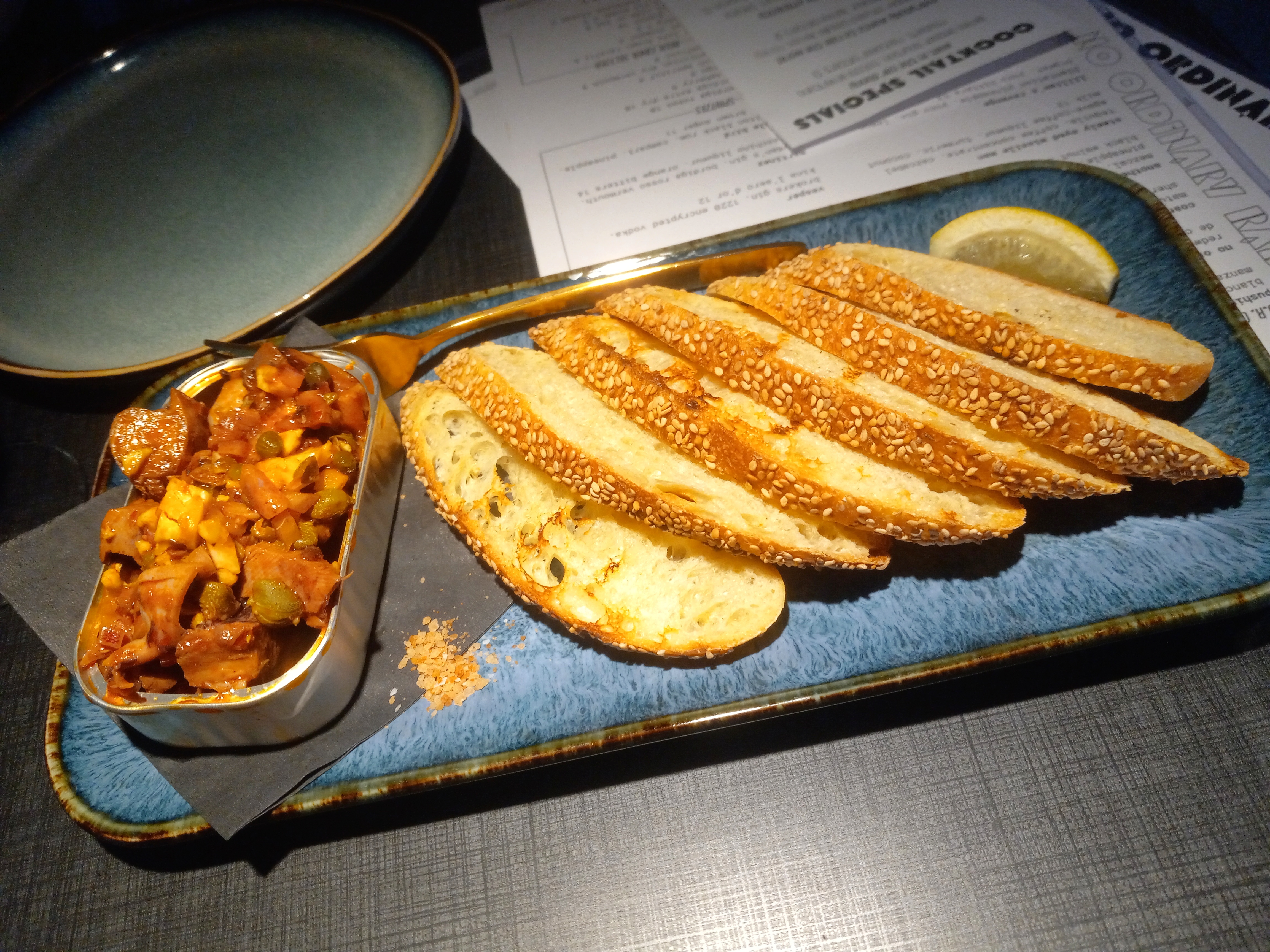 Squid pieces in a tin next to a stack of toasted bread slices