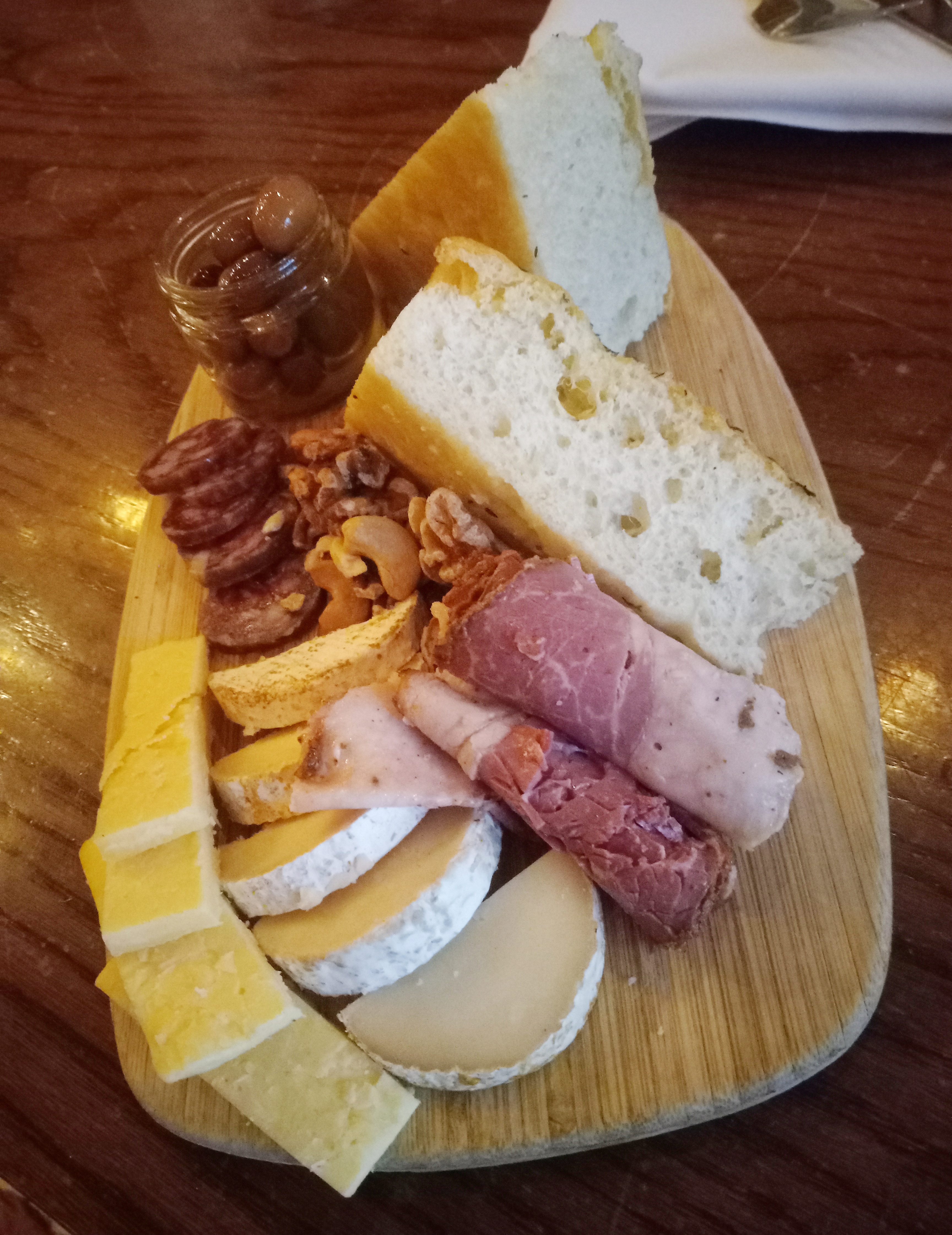 A board filled with various cheeses, meats, and thick slices of bread
