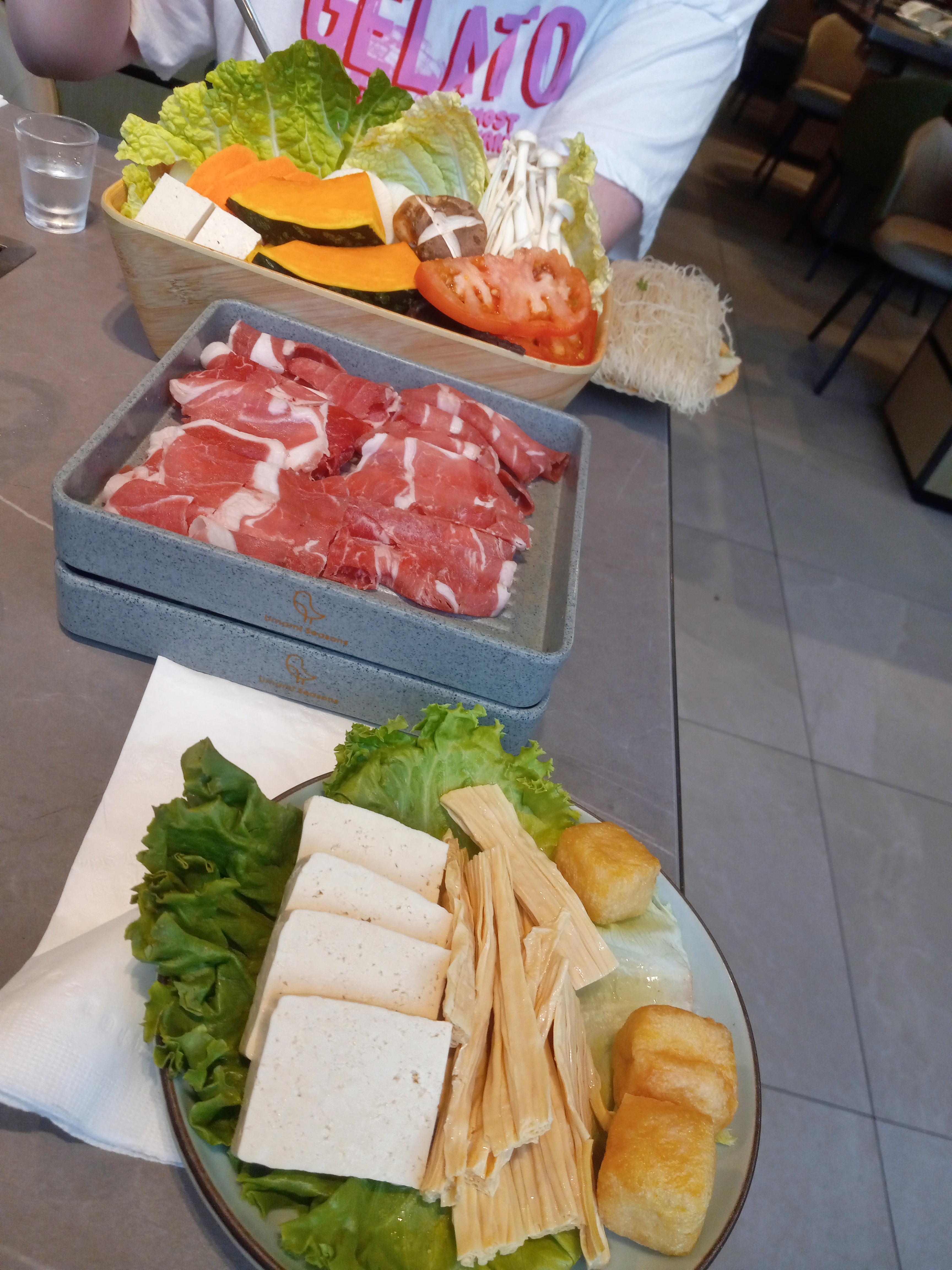 Various plates filled with raw meats, vegetables, and tofu